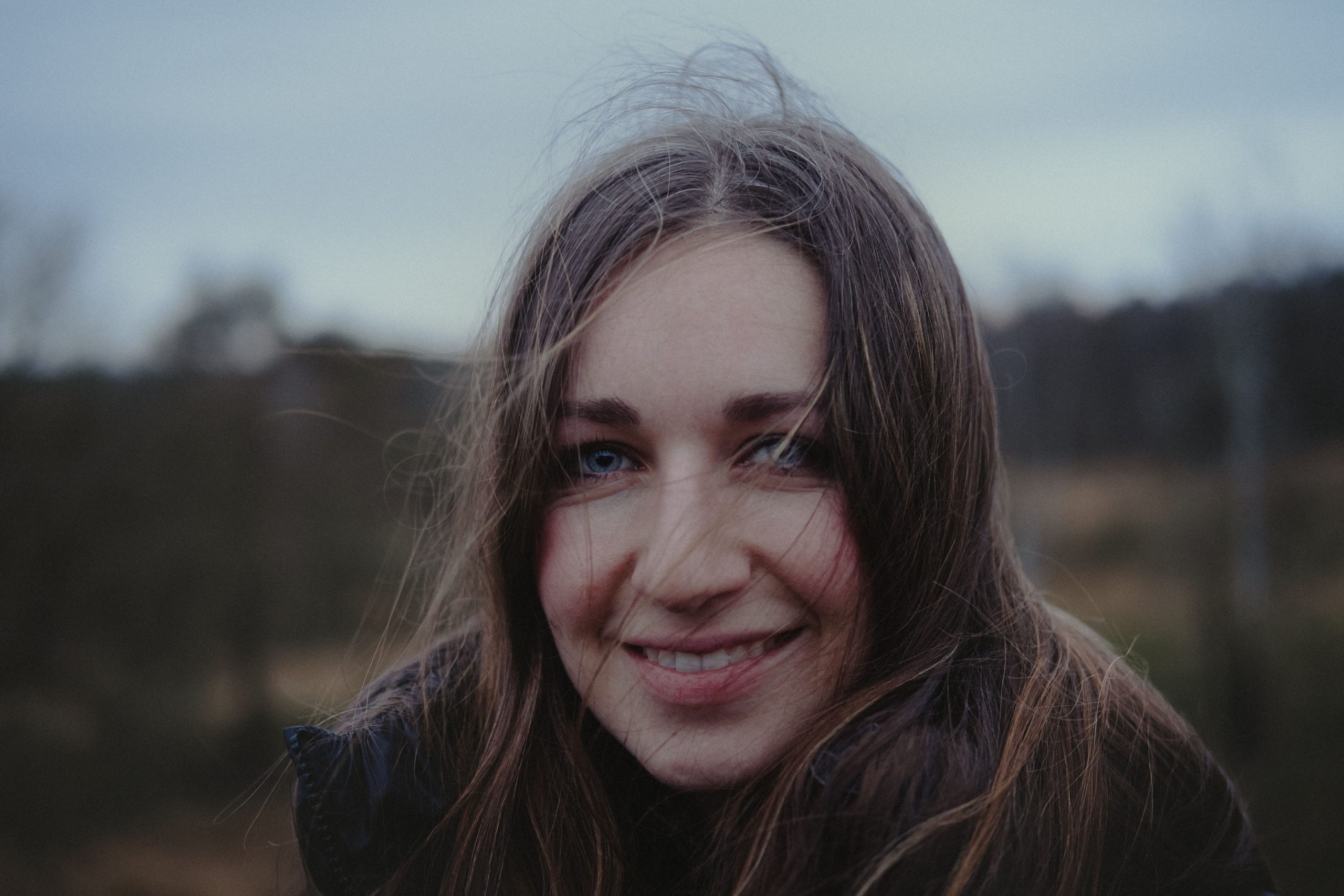 Natural close-up portrait of a smiling woman outdoors with an unposed, authentic expression.